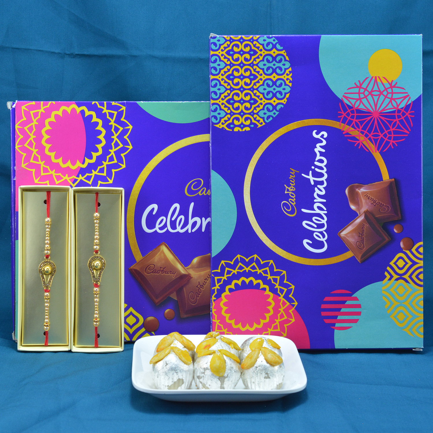 Awesome Eye Catching Shivling Rakhi with Delicious 2 Pcs Cadbury Celebrations along with Mouthwatering Kaju Badam Laddu