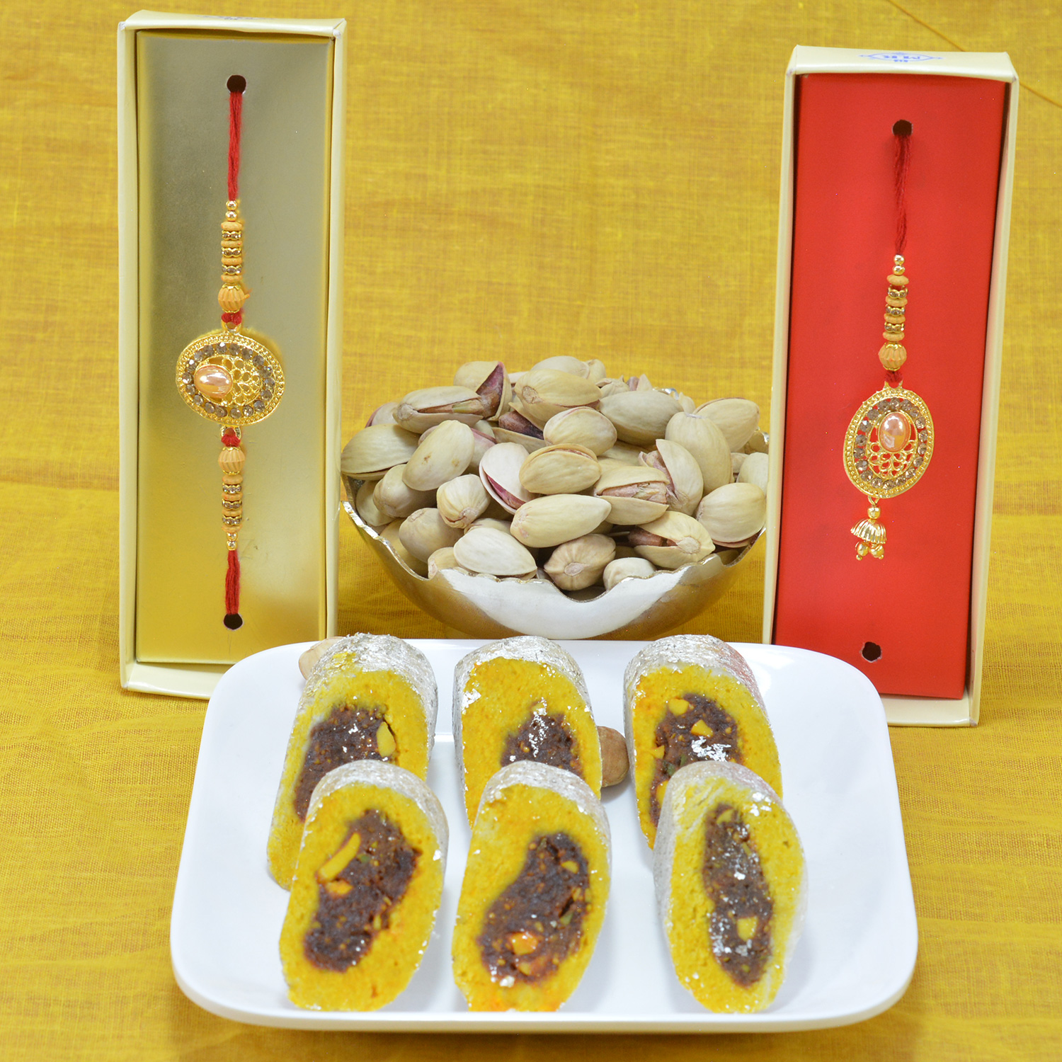 Piquant Kaju Rajbahar with Luscious Pista Dry Fruit along with Golden Theme Bhaiya  Bhabhi Rakhi Hamper