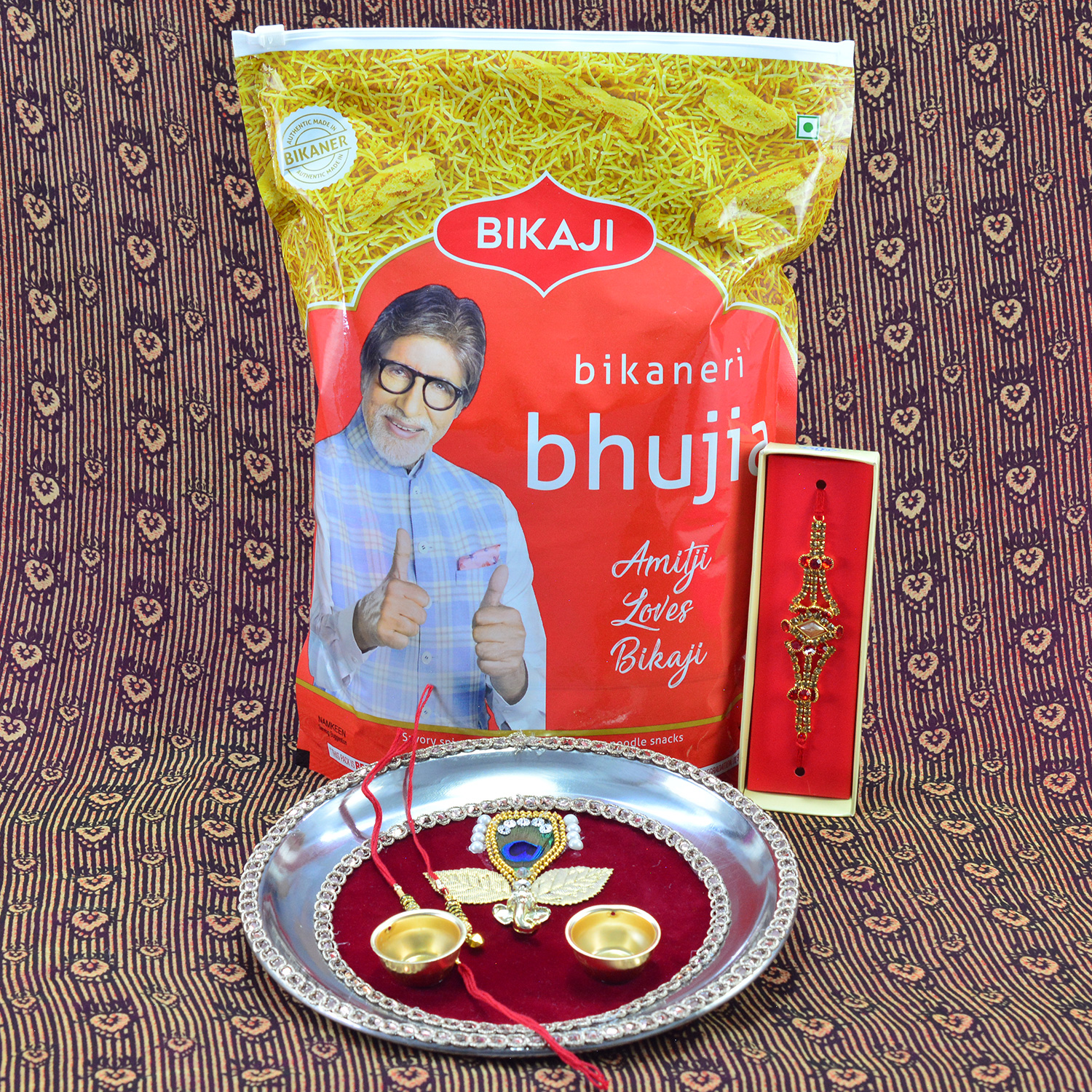 Branded Bikaji Bhujia Namkeen with Maroon Base Leaf and Ganesha Studded Rakhi Pooja Thali