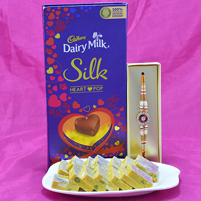 Mouthwatering Kaju Kesar Pista Barfi with succulent Cadbury Dairy Milk Silk along with Amazing Diamond Jewel Rakhi Hamper