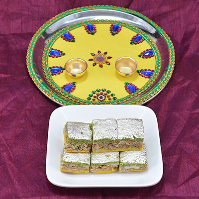 Beautifully crafted yellow painted Rakhi pooja thali with Delicious Badam Pista Barfi Hamper
