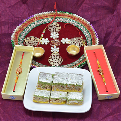 Beautifully Crafted Divine OM Pooja Thali with Badam Pista Barfi along with Stunning Sandalwood Rakhi Hamper