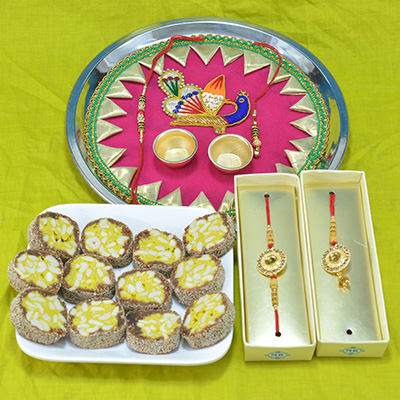 Beautfully Crafted Peacock Pooja Thali with Luscious Kaju Anjeer Pista Barfi along with Bhaiya Bhabhi Rakhi